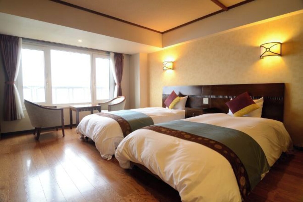 A hotel room with two beds, a desk, and a chair.
