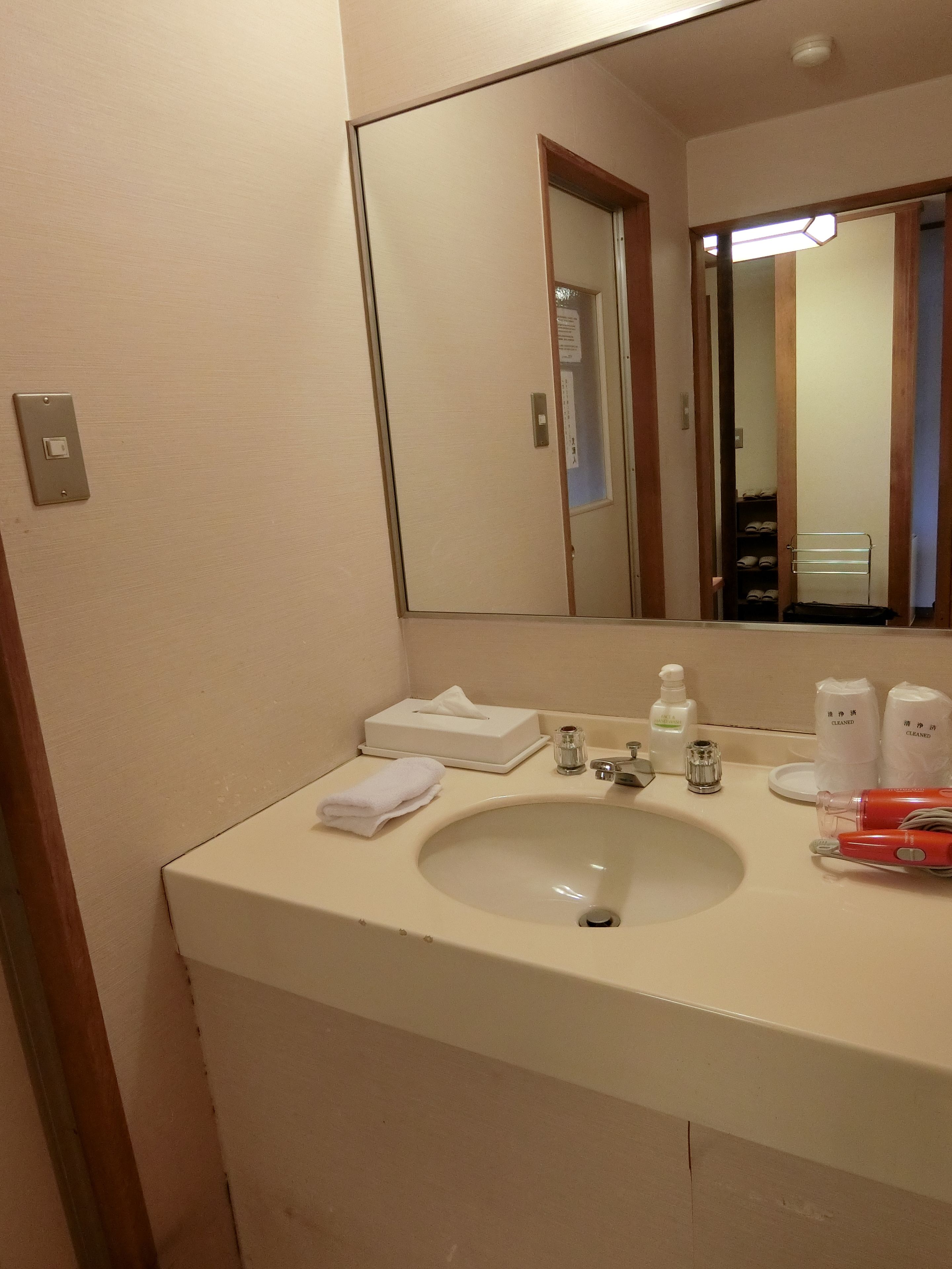A bathroom with a sink, mirror, towel, and toiletries.