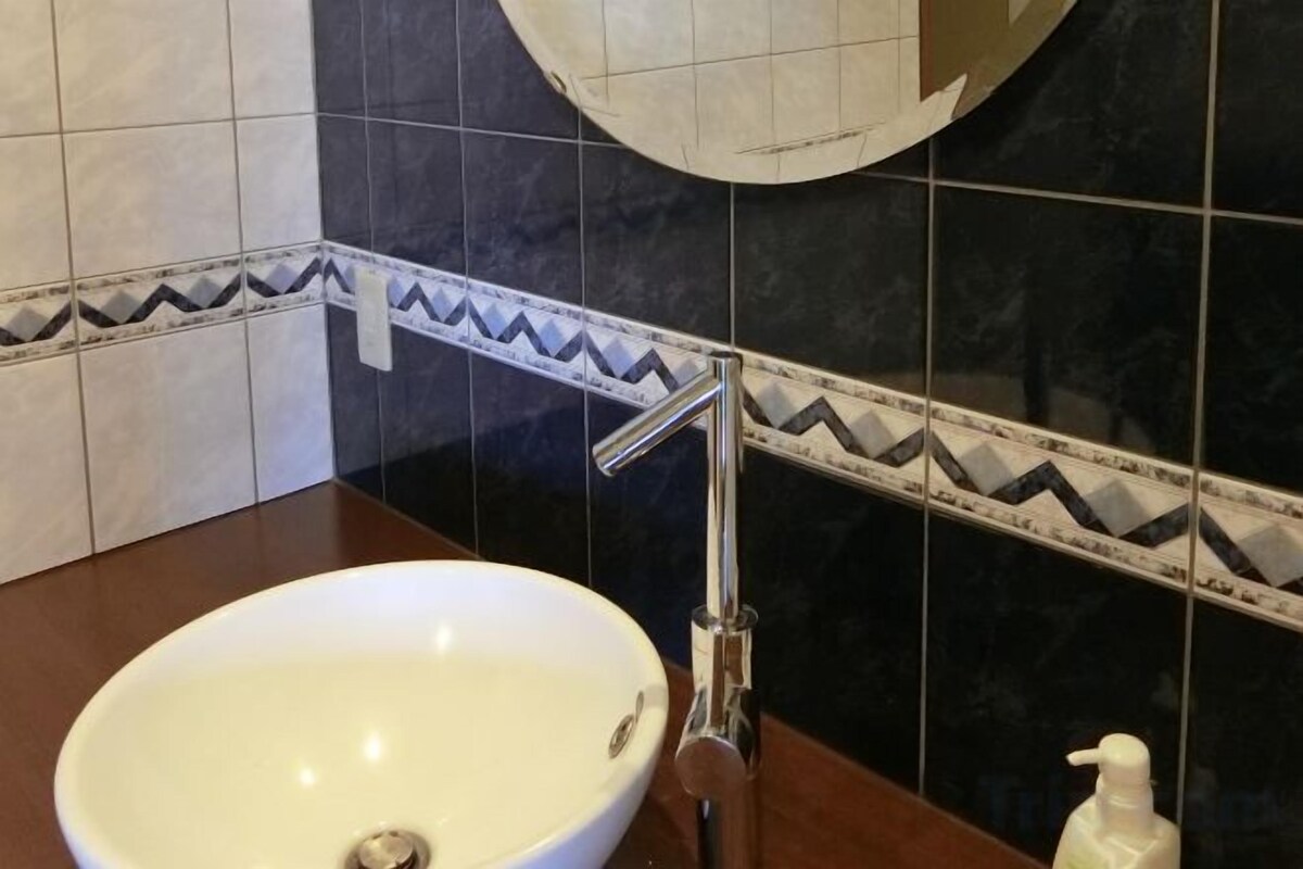 Une salle de bain avec un lavabo blanc, un miroir et un distributeur de serviettes.