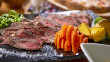 A charcuterie board with sliced meat, vegetables, and a glass of beverage.