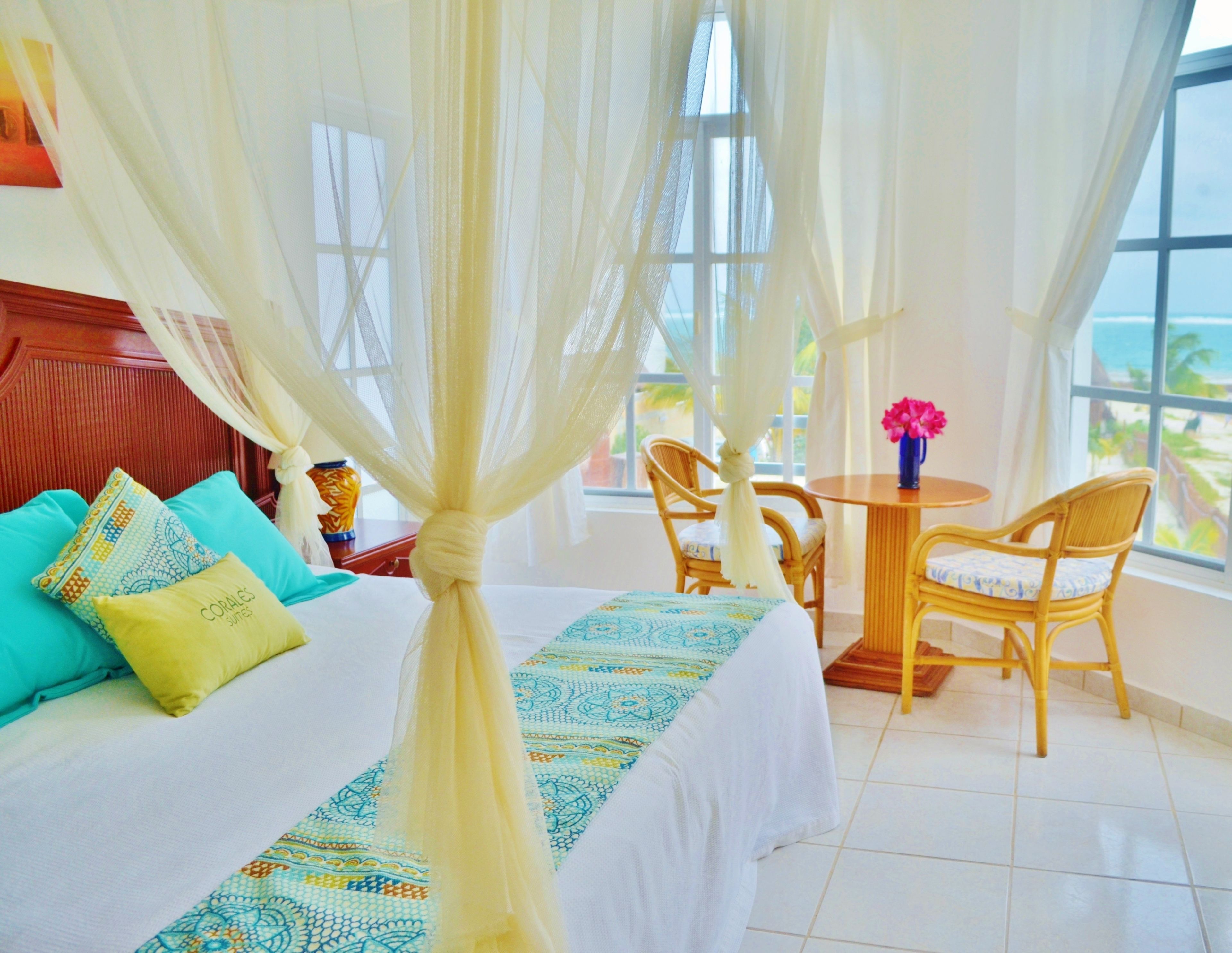 A hotel room with a bed, a table with chairs, and a view of the ocean.