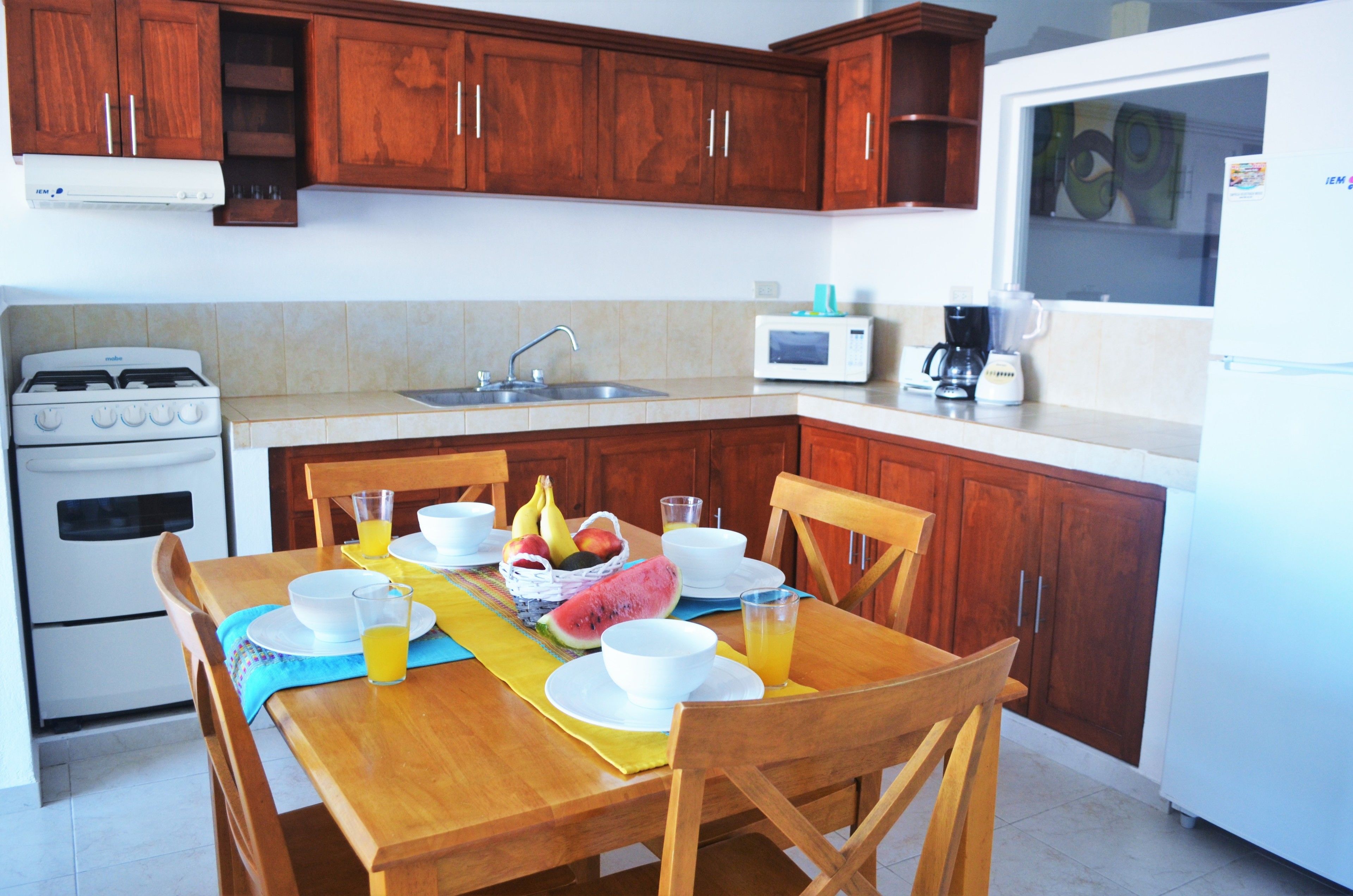 A kitchen with wooden cabinets, a stove, a microwave, and a refrigerator.