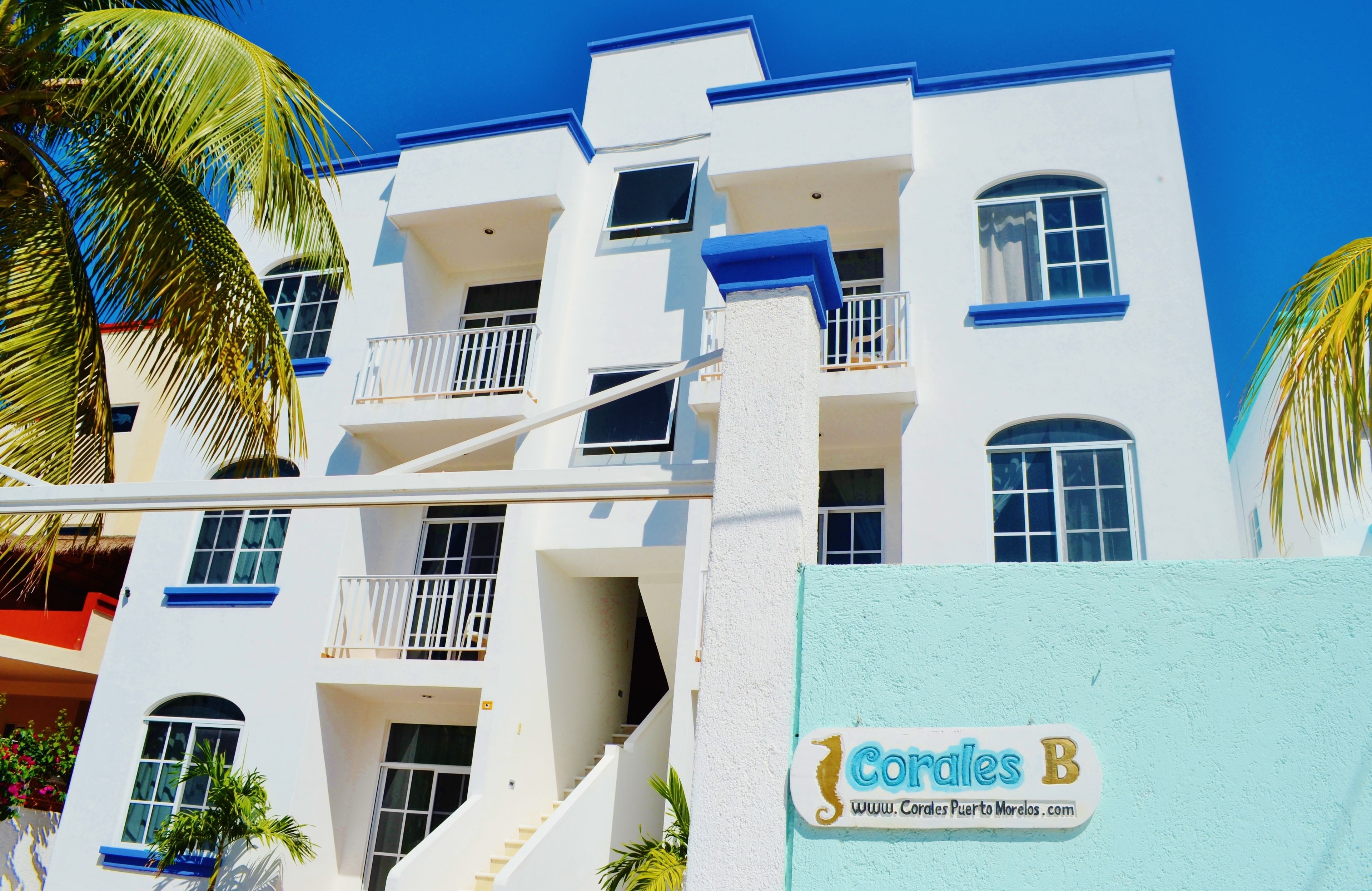 A multi-story hotel with balconies, a staircase, and a sign reading "Corales B".