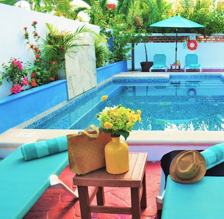 Una piscina al aire libre, sillones reclinables de piscina