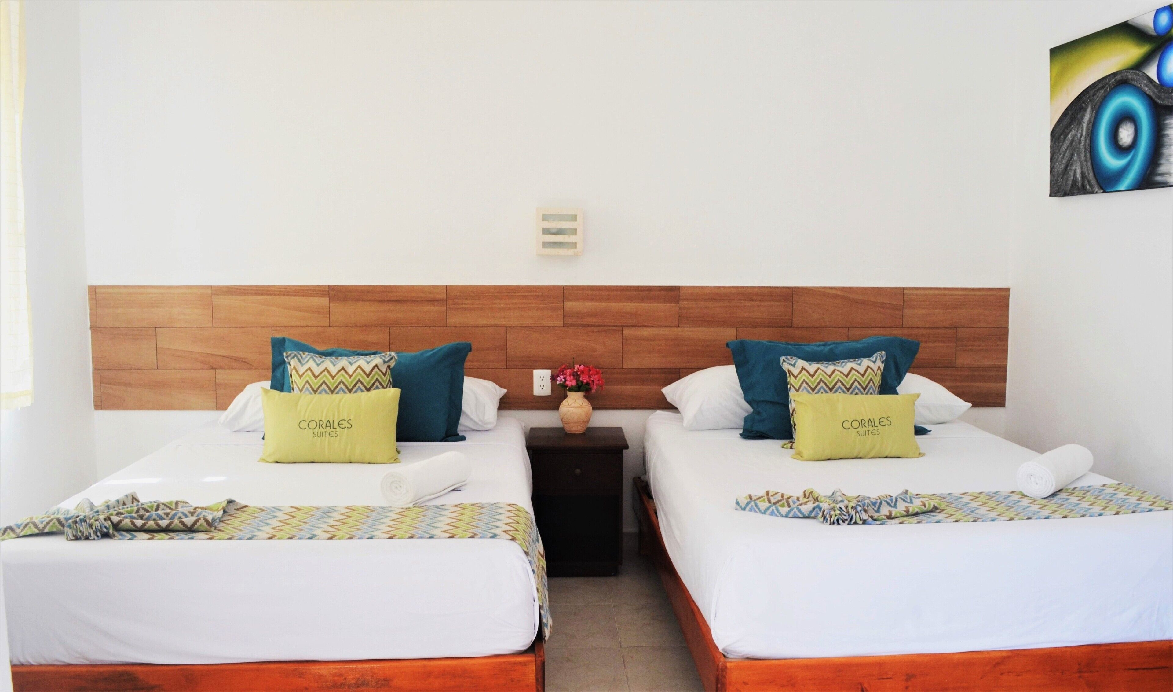 Een hotelkamer met twee bedden, een houten hoofdbord en een nachtkastje met een bloemenvaas.