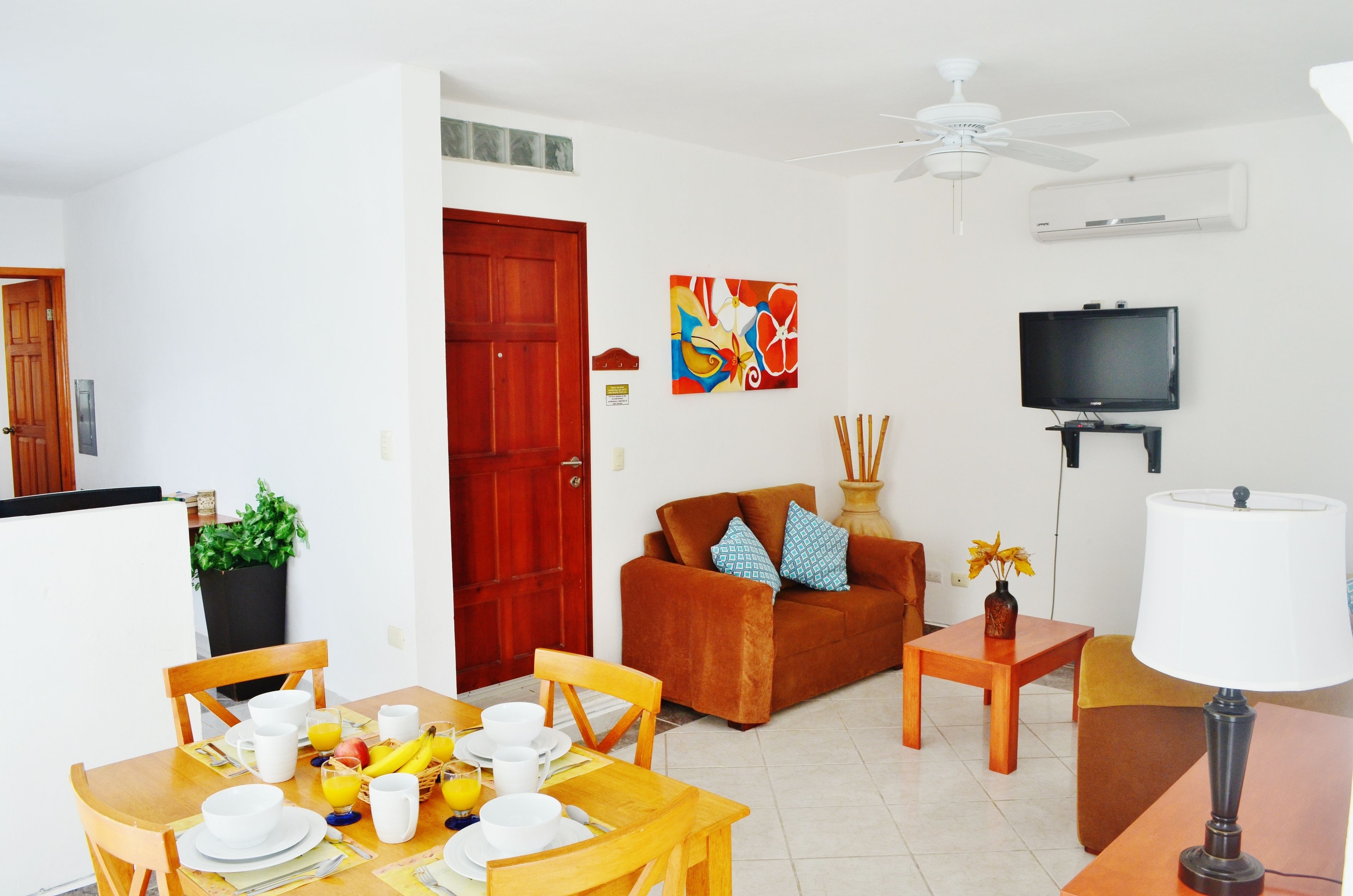 A living room with a sofa, TV, and dining area with a table set for two.