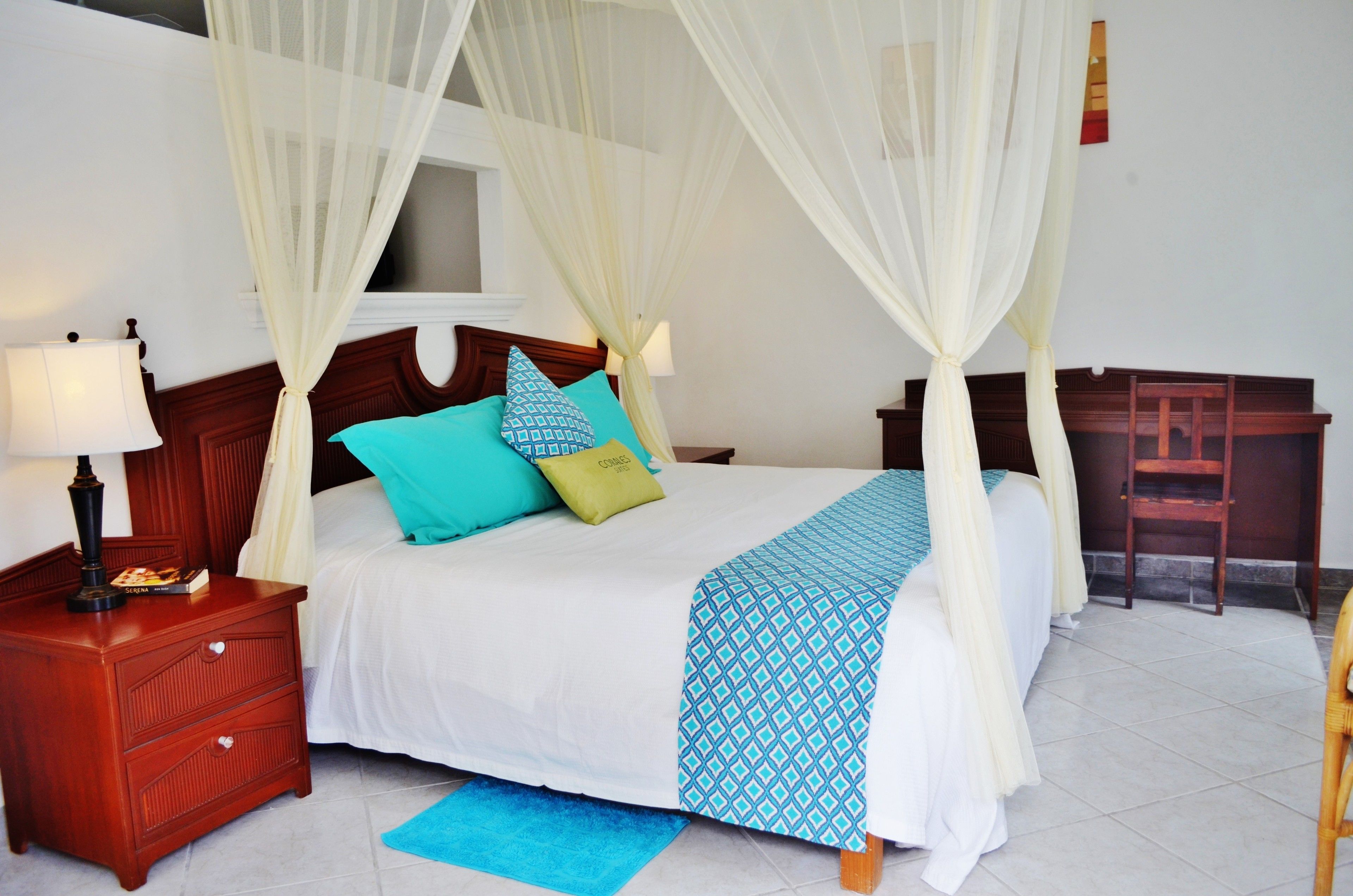 A neatly arranged bedroom with a bed, bedside tables, a nightstand, and a chair.