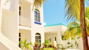 A multi-story building with balconies, a central courtyard, and palm trees. - Corales Suites (Puerto Morelos)