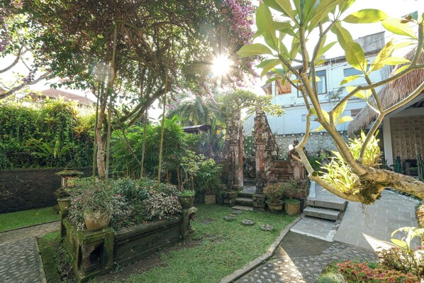A garden with a stone pathway, potted plants, and a small shrine. - Artini 2 Cottages (Ubud)