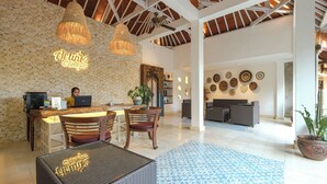 Un vestíbulo amplio con mostrador de recepción, zona de estar y decoración mural.