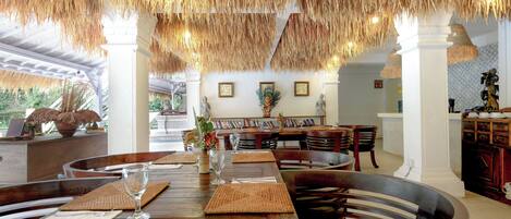 A dining area with a wooden table, woven placemats, and a large bowl centerpiece.