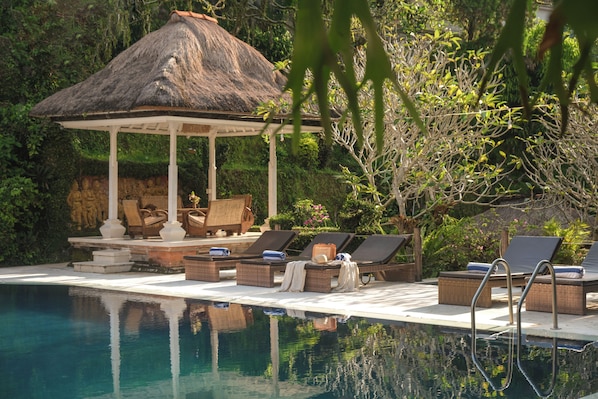 Una piscina al aire libre, sombrillas, sillones reclinables de piscina