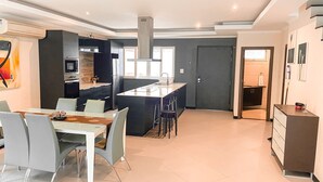 A modern kitchen with a central island, dining area with chairs, and a small kitchenette. - Hidden Palm Pool Villas (Pattaya)