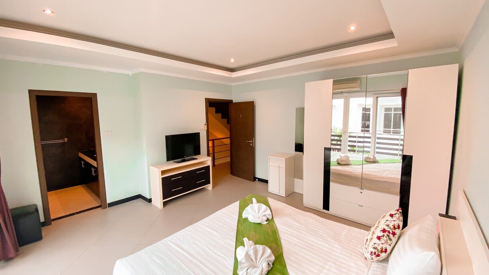 A hotel room with a bed, a TV, a desk, a wardrobe, and a balcony with a view.