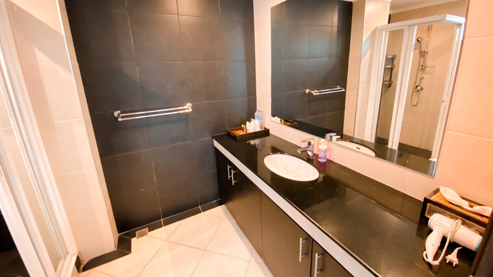 A modern bathroom with a black countertop, white sink, and a large mirror.