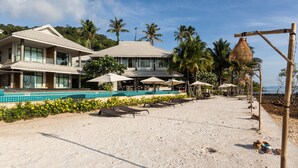 A beachfront property with a swimming pool, sun loungers, and a beach bar area. - Na Tara Resort (Ko Chang)