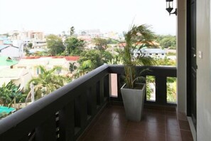 A balcony with a potted plant, a view of a cityscape, and a tiled floor. - Ploen Pattaya Residence by Tolani (Pattaya)