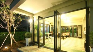 A modern house with a glass door leading to a patio area. - Ploen Pattaya Residence by Tolani (Pattaya)