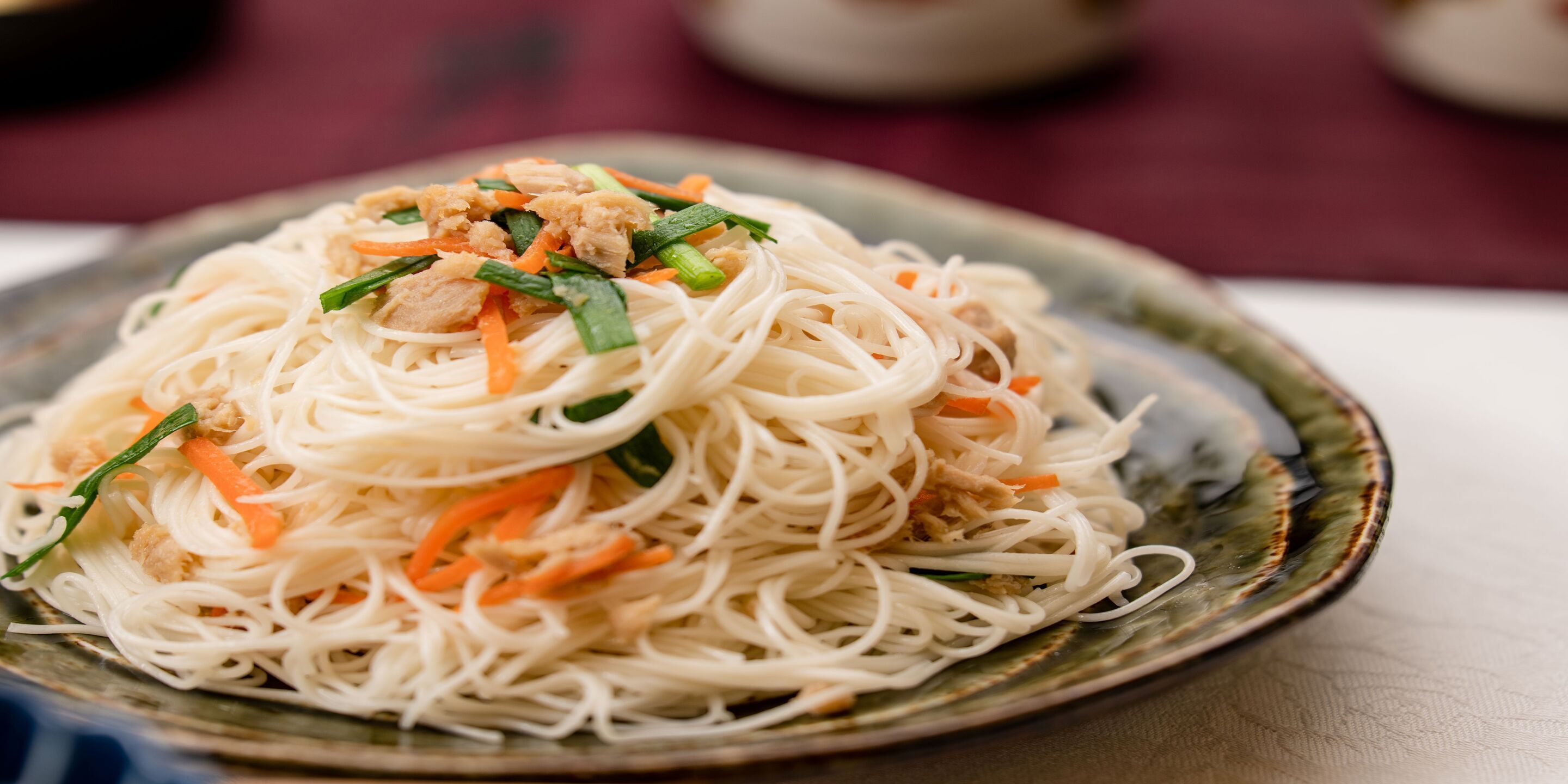 A plate of noodles with vegetables and meat.