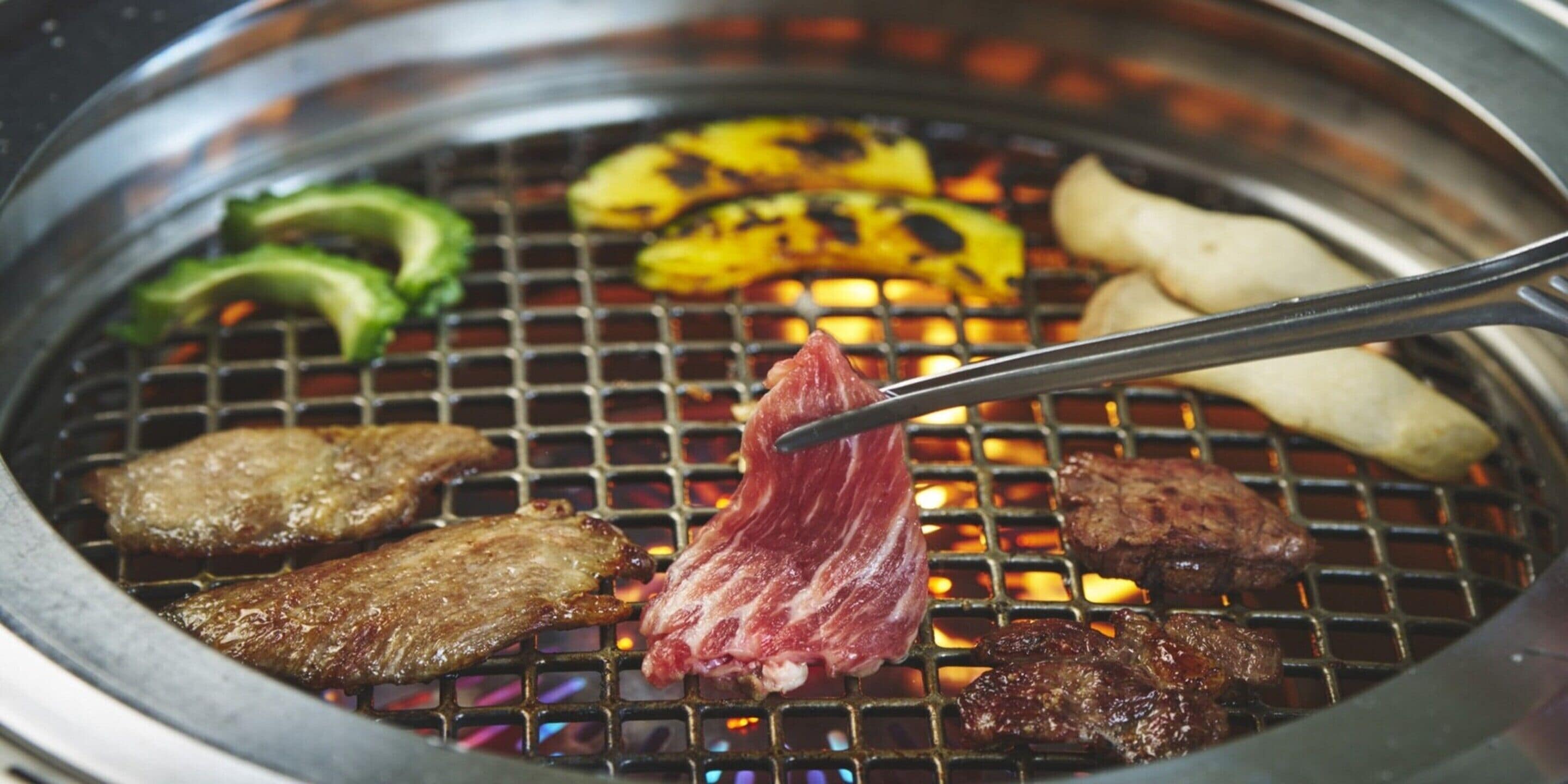 A grill with various meats and vegetables being cooked.