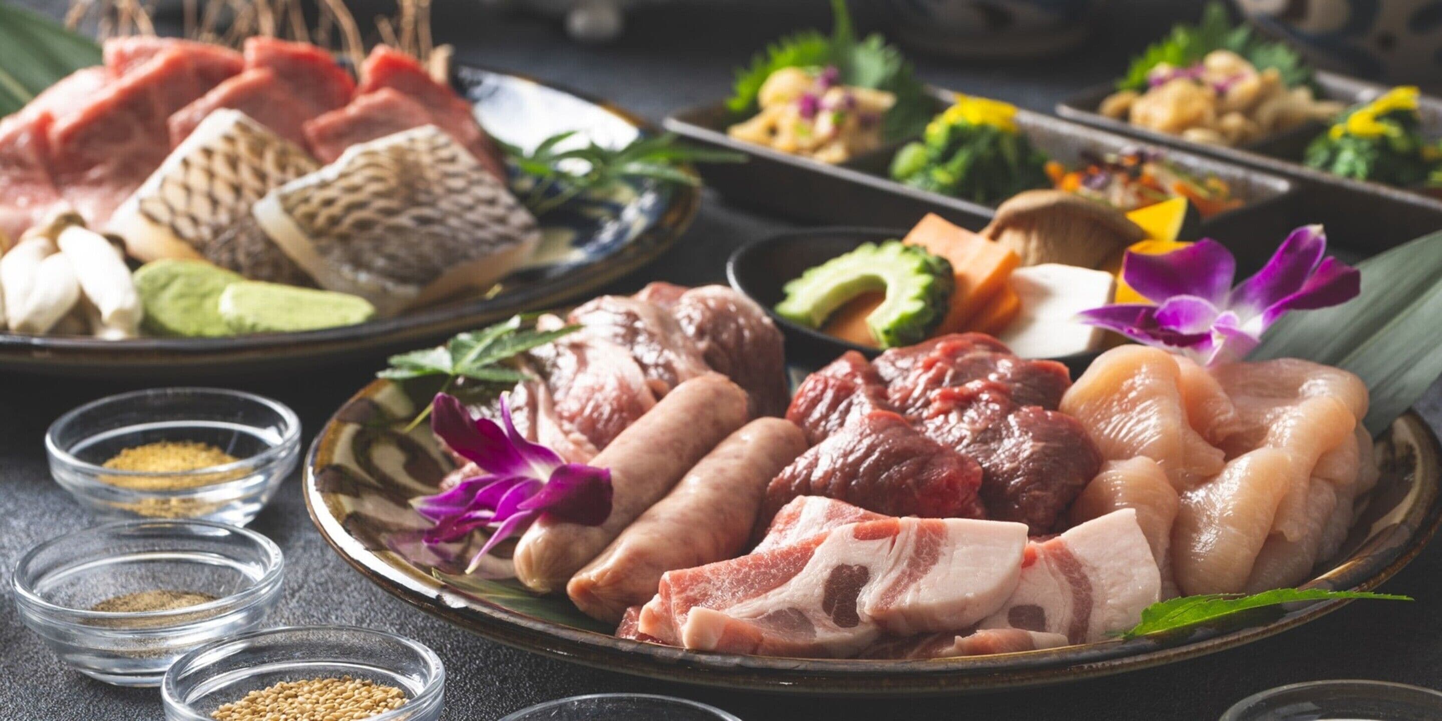 A variety of raw meats and vegetables on a plate, with small bowls of spices and herbs nearby.