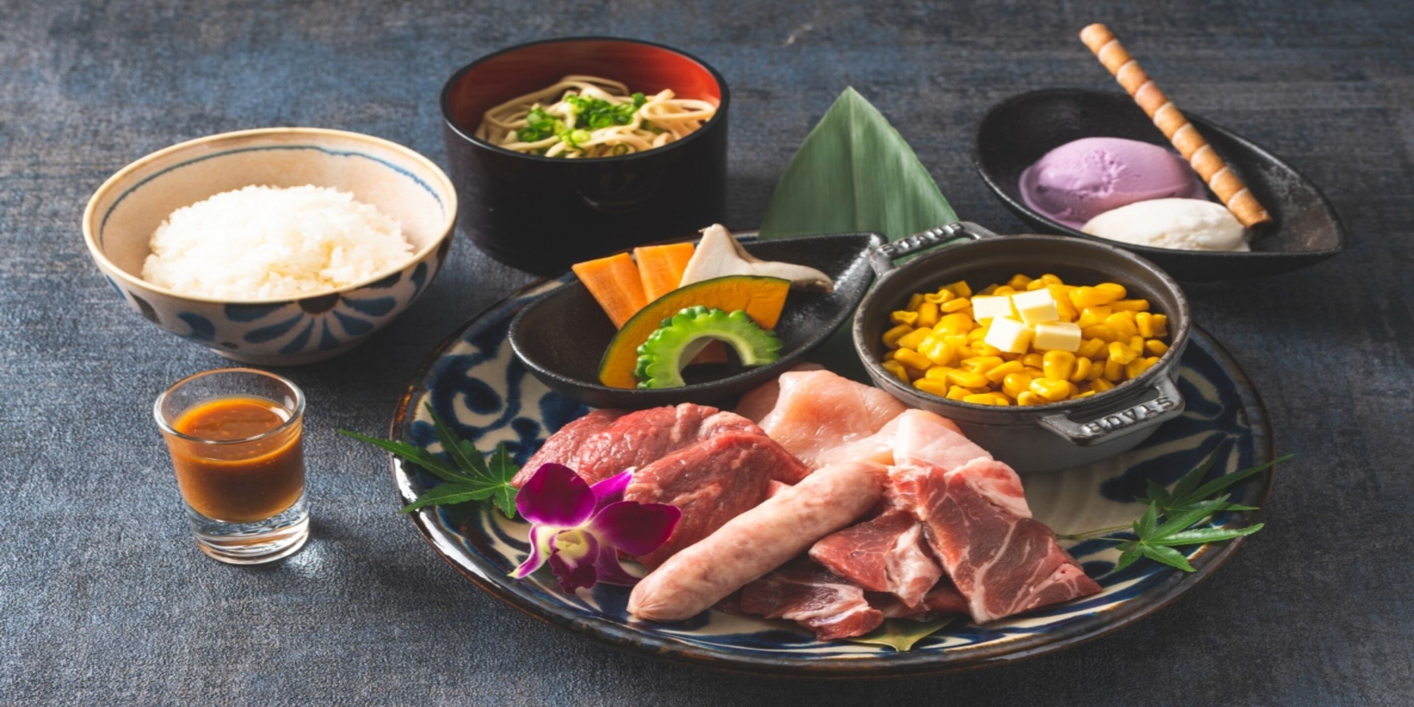 A traditional Japanese meal with rice, soup, meat, corn, and ice cream.