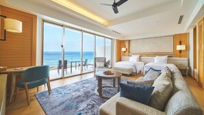 A modern hotel room with a large balcony, a bed, a sofa, a desk, and a chair.