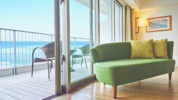 A green sofa with two cushions, a wicker chair, and a wooden floor.