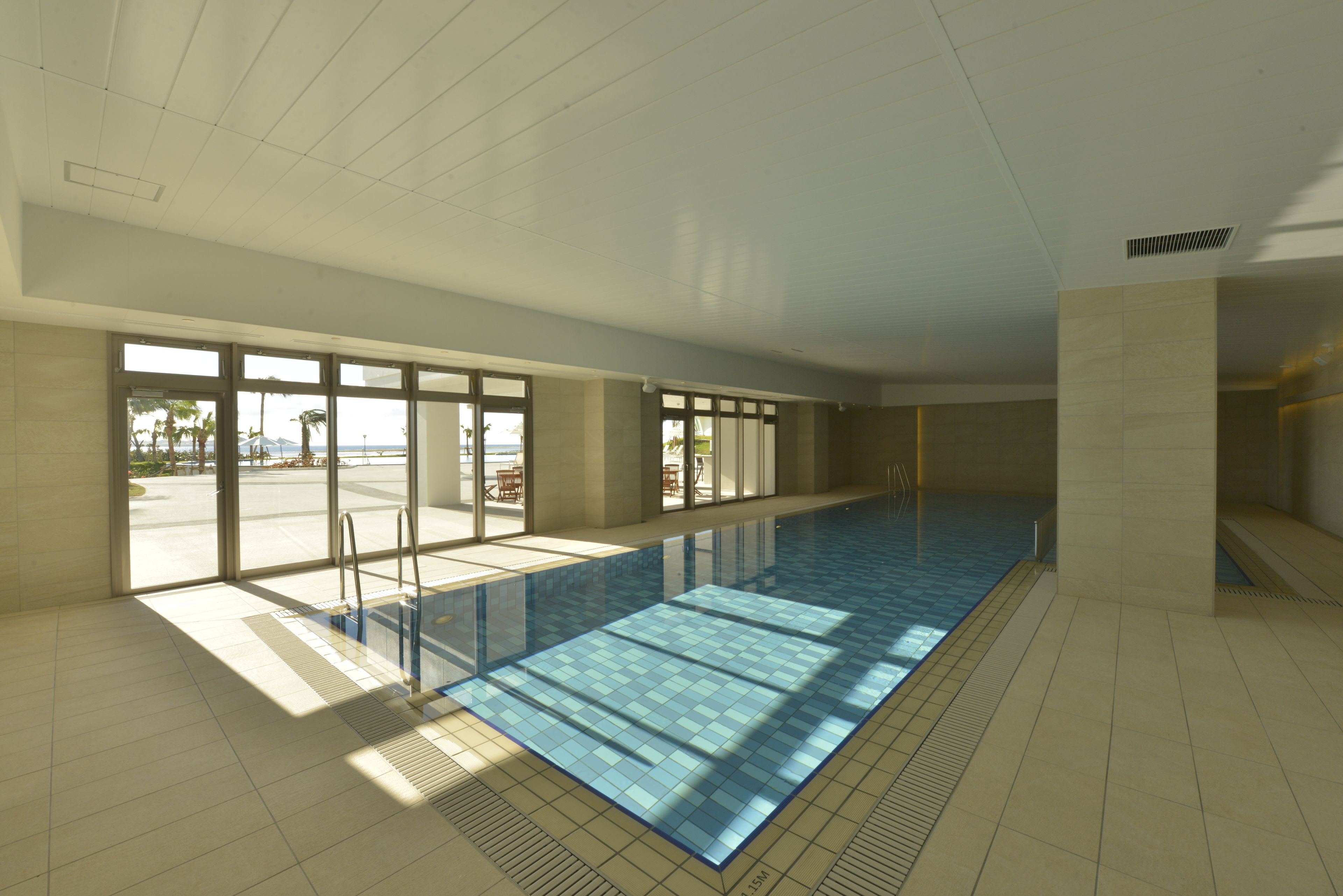 A large indoor swimming pool with clear glass walls, allowing views of the outdoors.