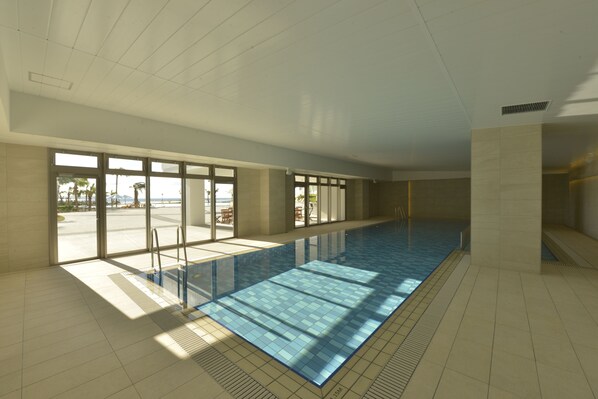 Una amplia piscina interior con paredes de vidrio transparente que ofrecen vistas al exterior.