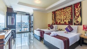 Een hotelkamer met twee bedden, een bureau en uitzicht op de stad.