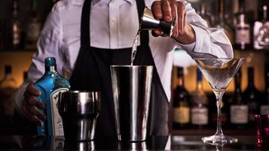 A bartender pouring a drink from a bottle into a shaker. - Theater Hotel (Antwerp)