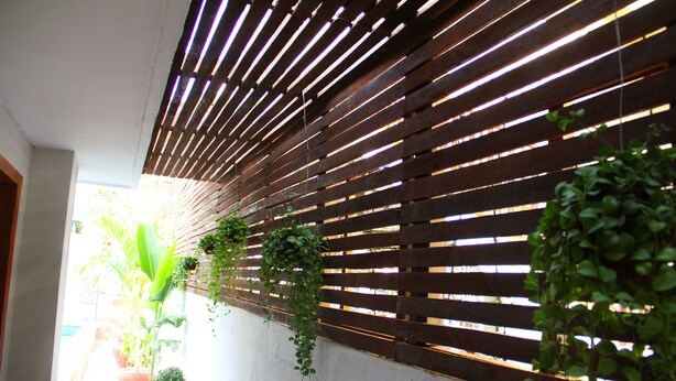 A narrow corridor with a wooden slatted wall and potted plants. - Cozy Boutique Hotel (Phnom Penh)