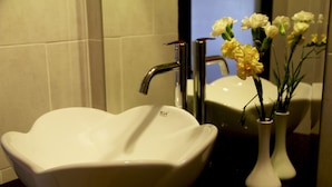 A bathroom with a white vessel sink and a vase with flowers. - Cozy Boutique Hotel (Phnom Penh)