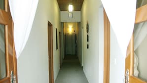A narrow hallway with wooden doors and a carpeted floor, leading to a room with a light fixture and a framed picture on the wall. - Cozy Boutique Hotel (Phnom Penh)