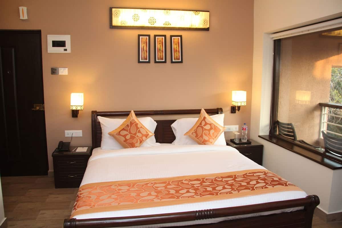 Habitación de hotel con cama, lámparas de noche, mesita de noche, escritorio con teléfono y ventana con vistas.