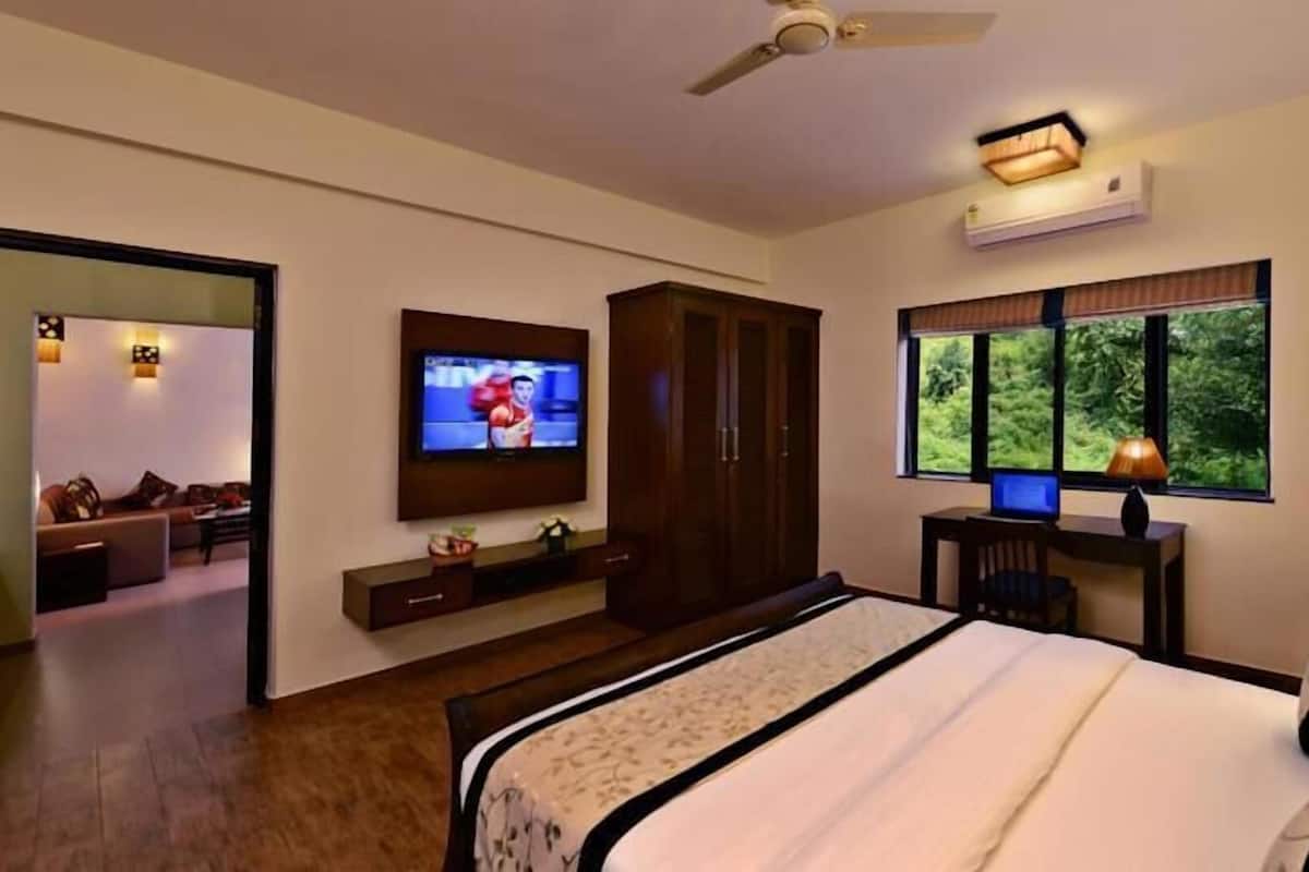 Un dormitorio moderno con cama, televisión, armario y escritorio con computadora.