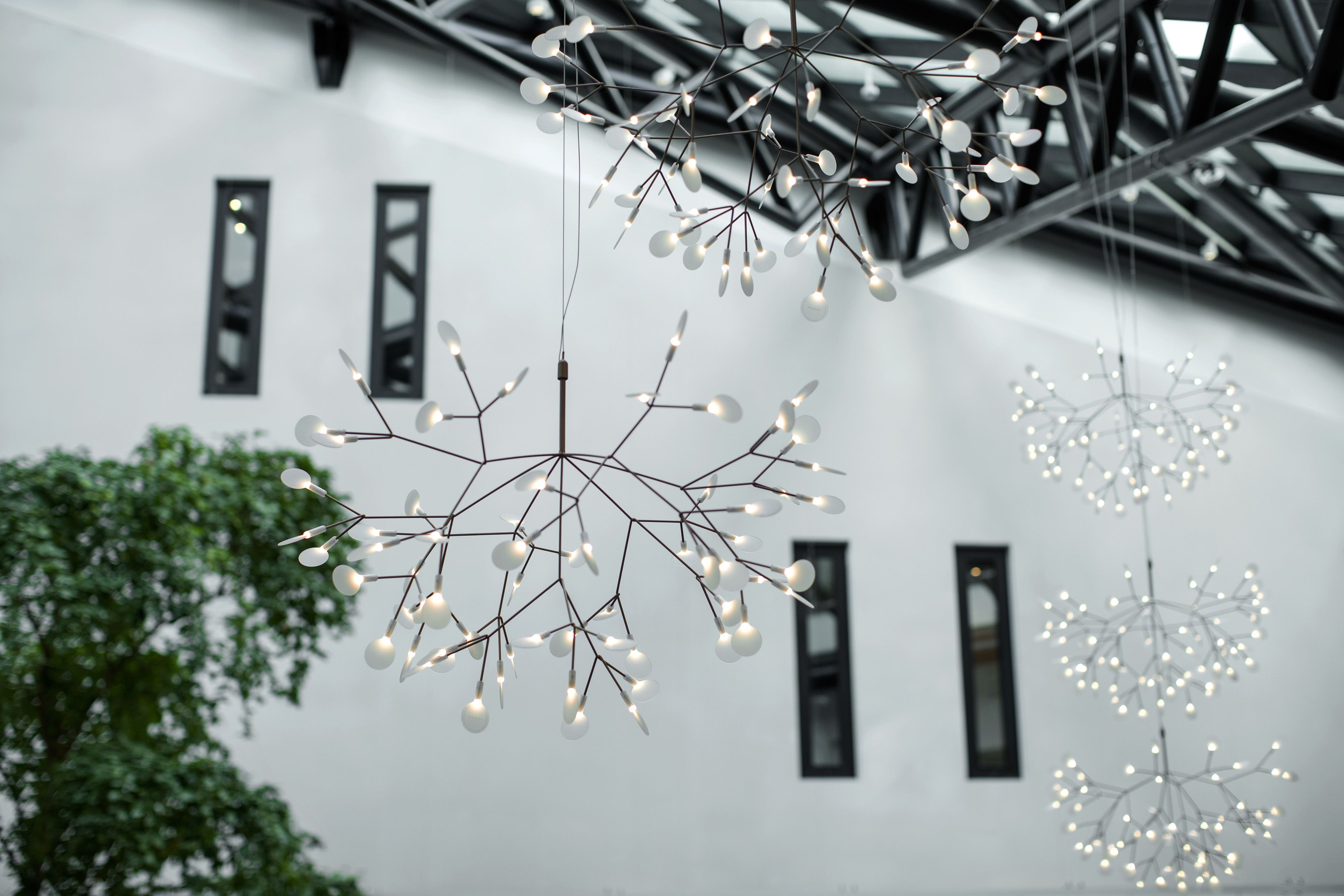 A modern interior with hanging light fixtures and a white wall with windows.
