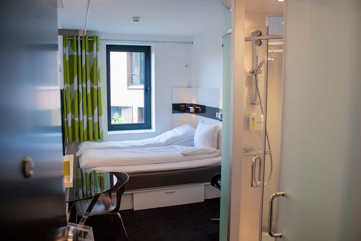 Ein Hotelzimmer mit einem Bett, einem Schreibtisch und einer Dusche.