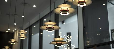 Multiple pendant lights hanging from the ceiling in a modern interior space with large windows.
