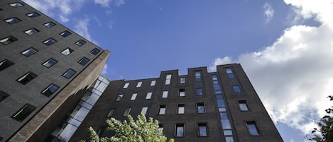 A tall building with a modern architectural design, featuring multiple windows and a brick facade.