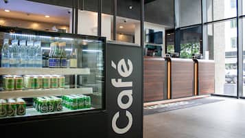 Um café com uma vitrine de vidro contendo água engarrafada e bebidas enlatadas.