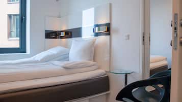 Et moderne hotelværelse med en pænt redt seng, et glastilbordsbord og en stol.