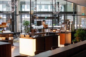 A modern bar area with a counter, seating, and a view of the street through large windows.