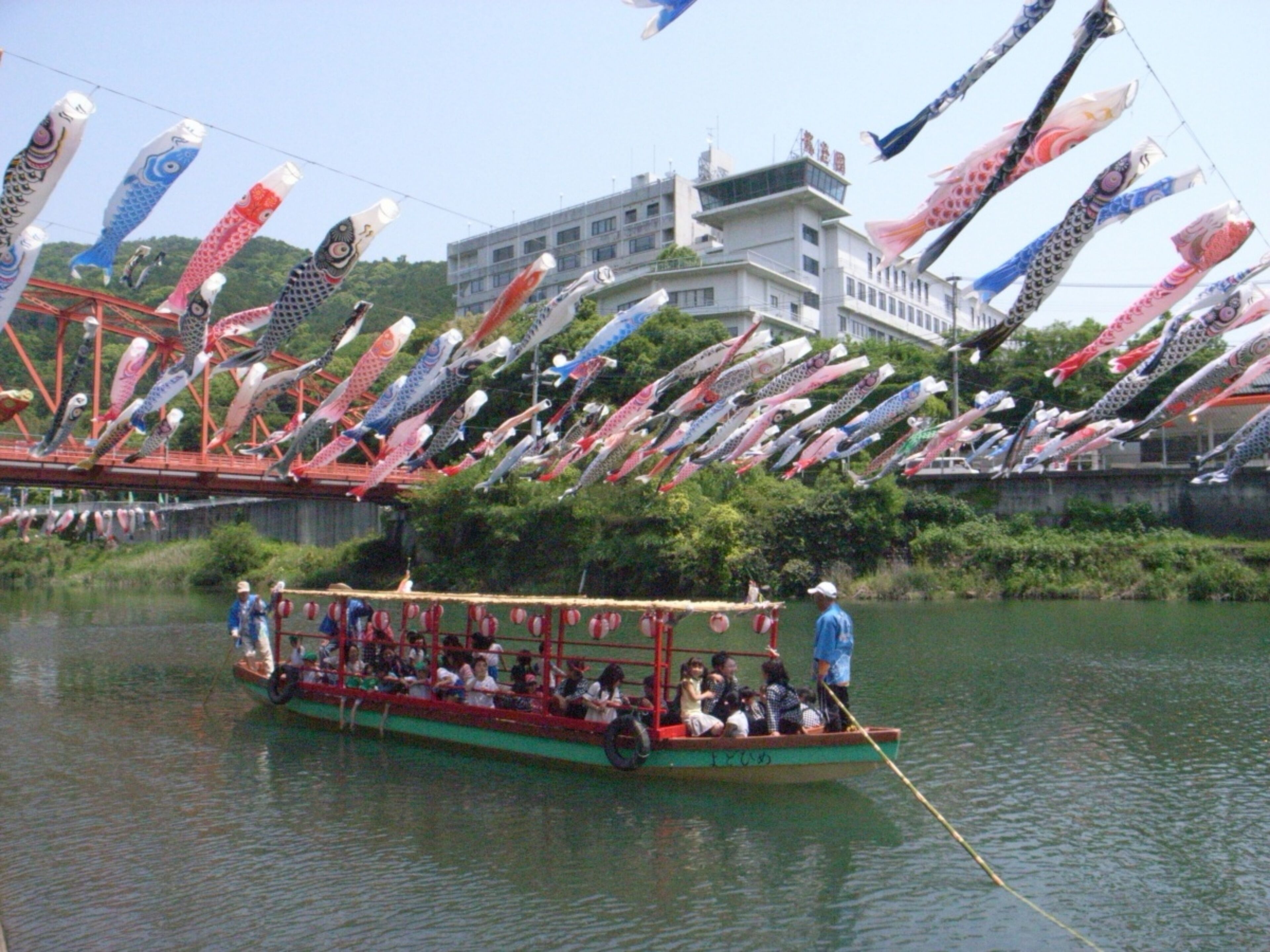 Un barco con pasajeros en un río, rodeado de numerosas banderas coloridas.