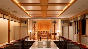 A hotel lobby with a long reception desk, seating areas, and a central decorative feature.