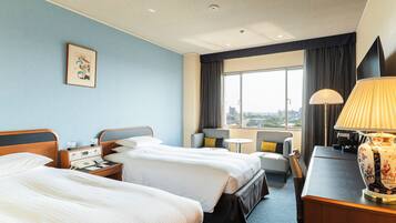 Hotelkamer met twee bedden, een bureau, een stoel, een lamp en een raam met uitzicht op de stad.