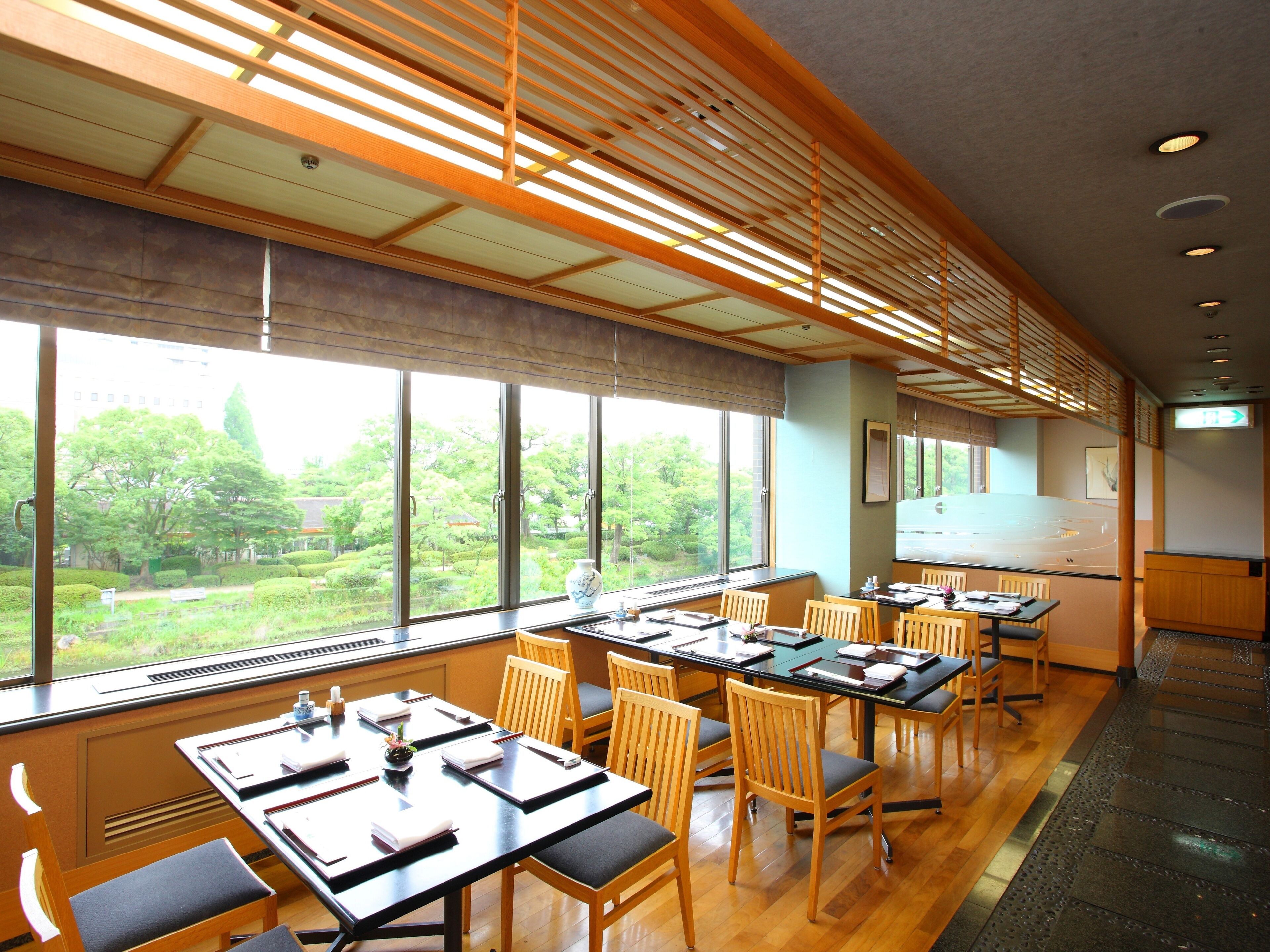 A conference room with large windows, wooden tables, and chairs.