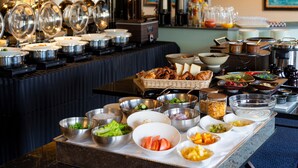 A buffet setup with various food items and kitchen equipment.