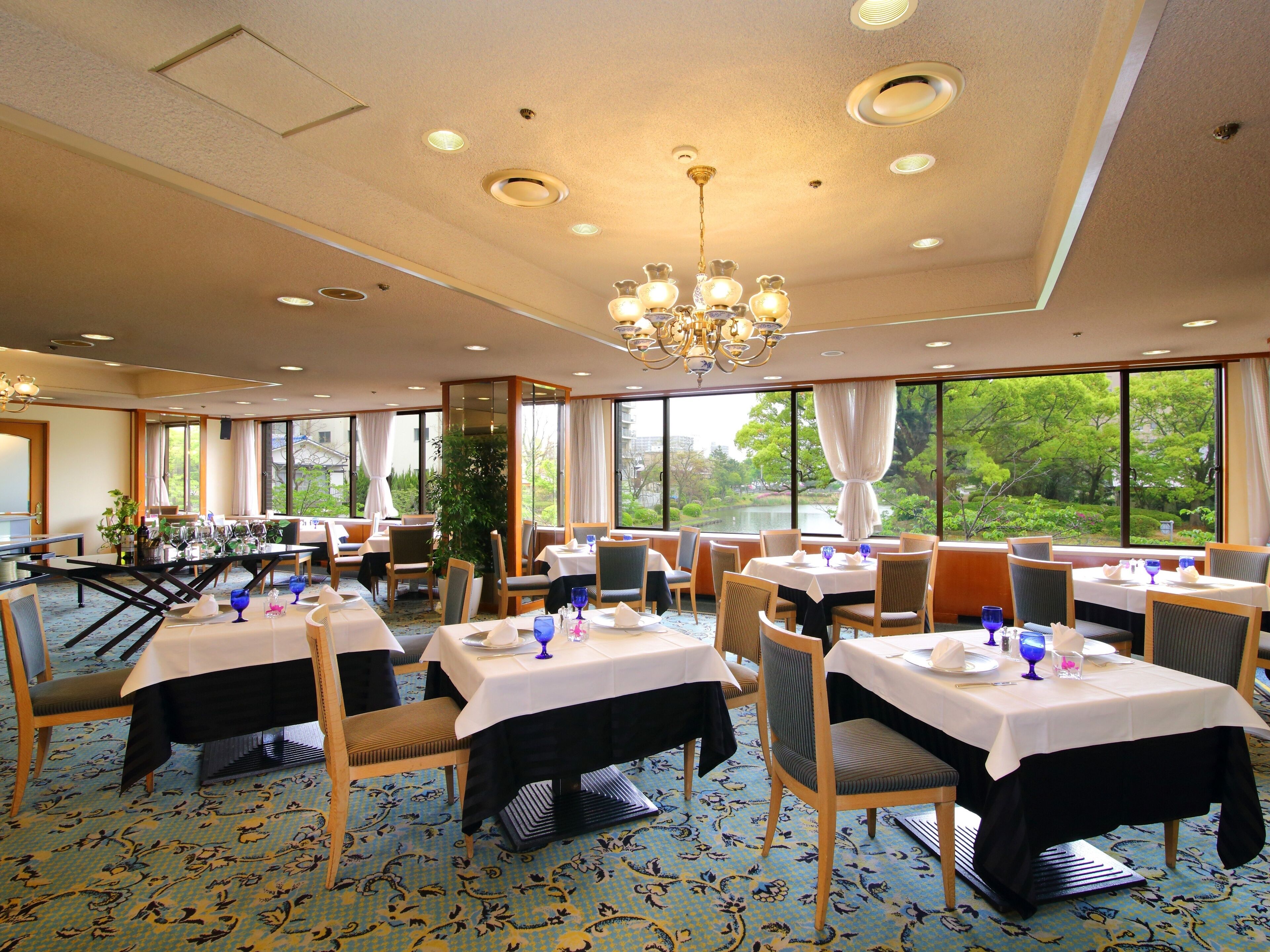 A restaurant with multiple tables, chairs, and a chandelier.